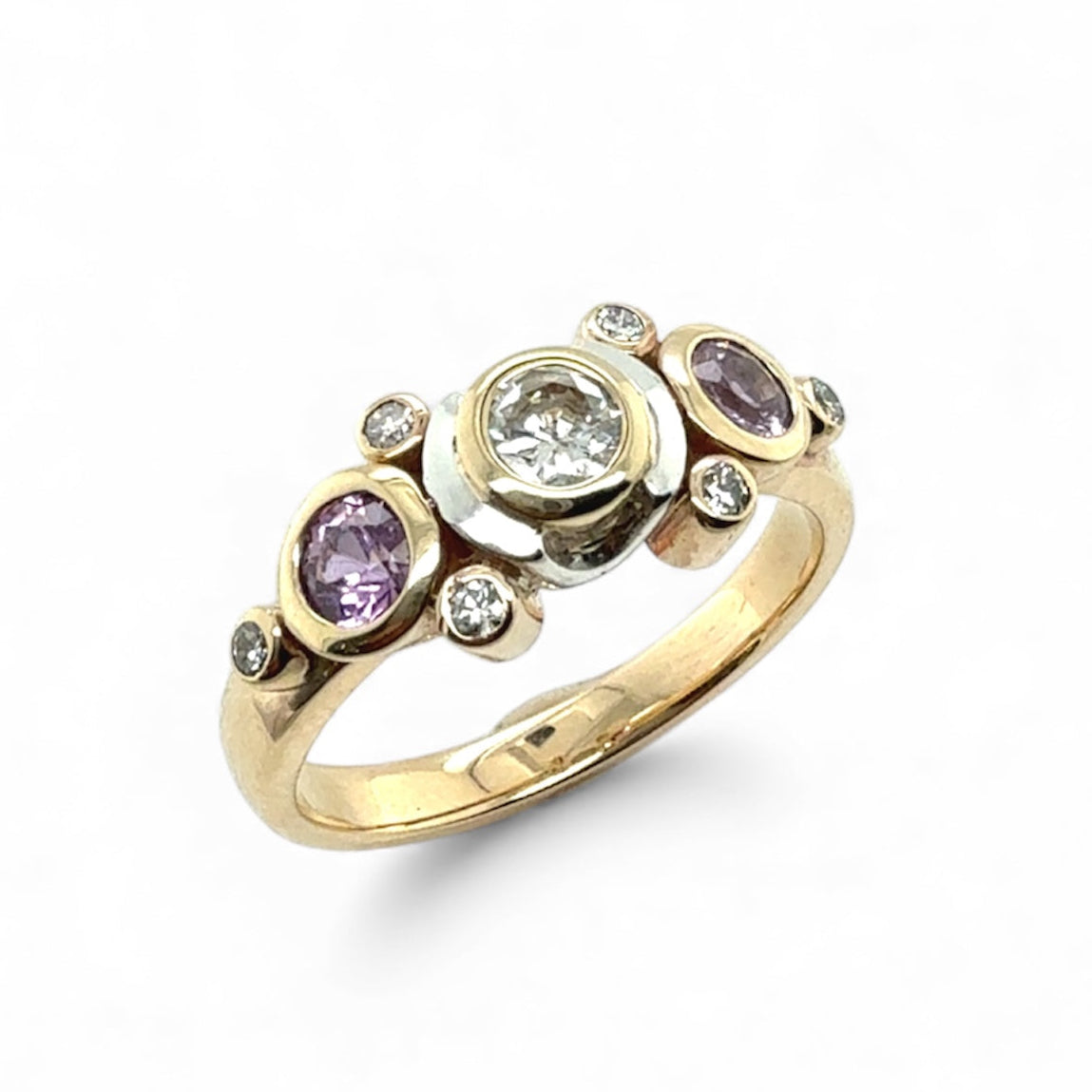Bespoke Gold ring with purple sapphire gemstones and diamonds on a white background