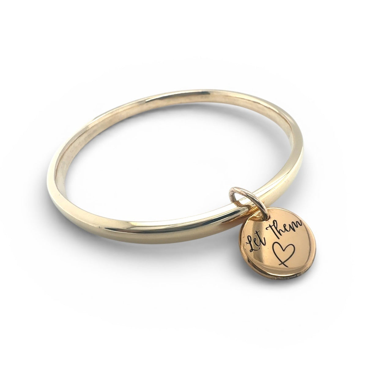 Solid gold bangle with ‘let them’ engraved onto a round charm attached to the bangle 
