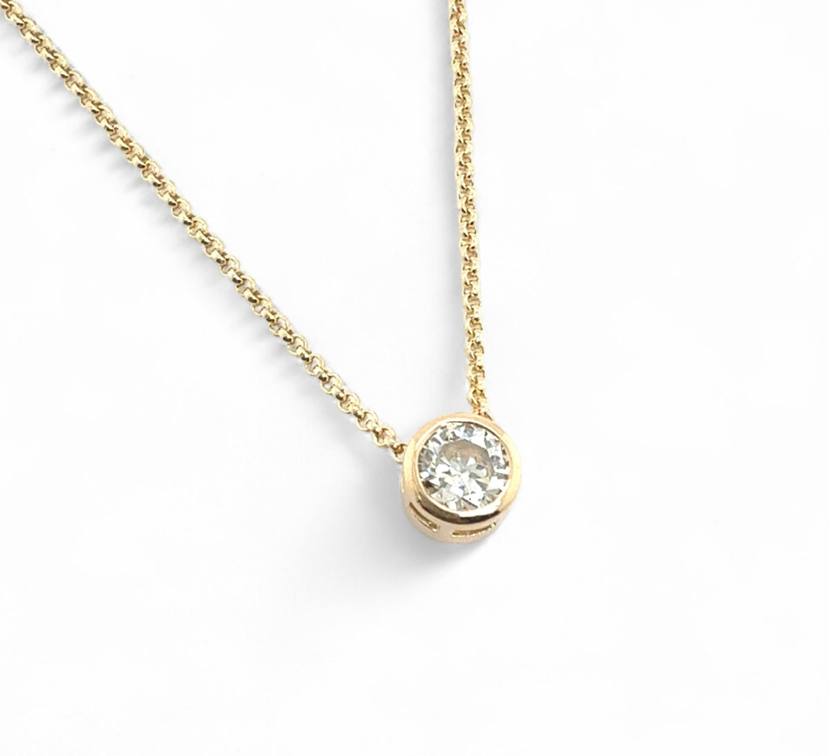 Gold sliding necklace with a diamond pendant on a white background