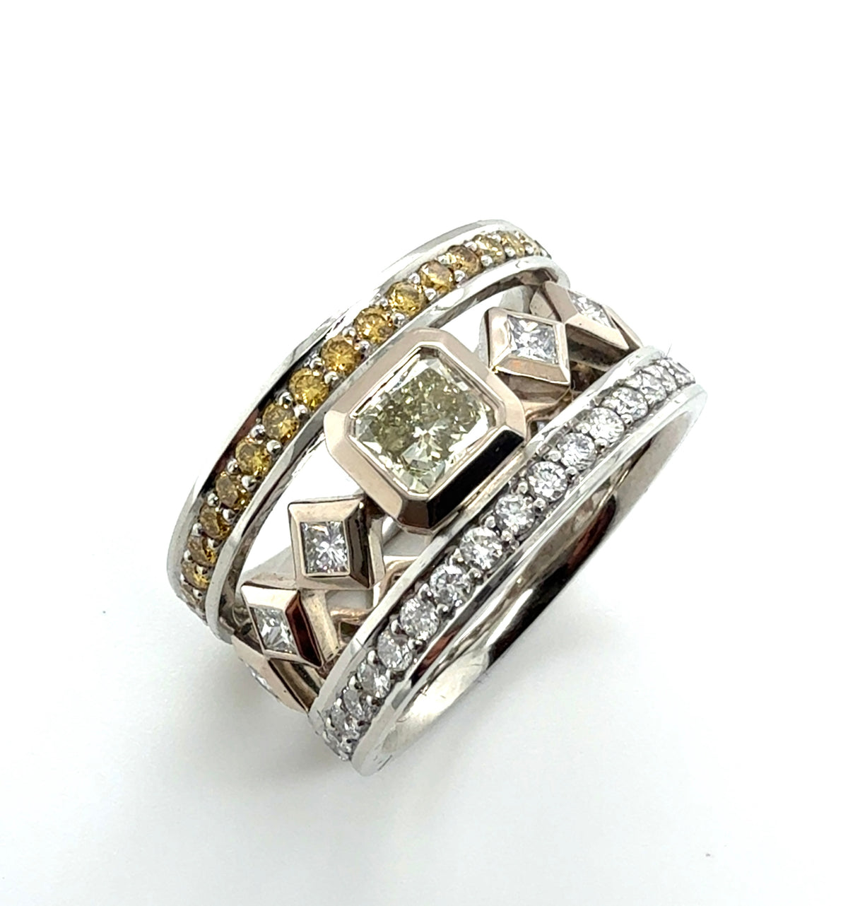 A multi-band ring featuring a central diamond-cut stone, surrounded by bands of yellow diamonds, clear pavé diamonds, and geometric diamond-shaped accents in silver and yellow gold-toned metal, set against a plain white background.